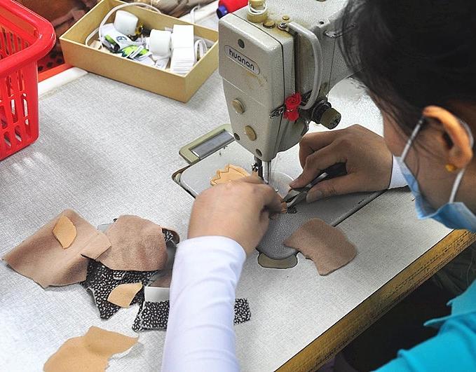 Sample maker hand-sewing a custom plush toy prototype